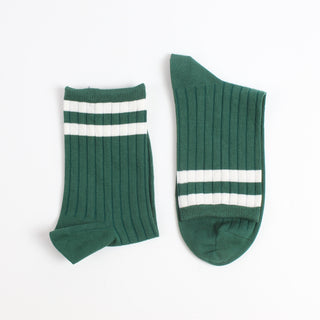 Two green socks with white stripes on a light gray background