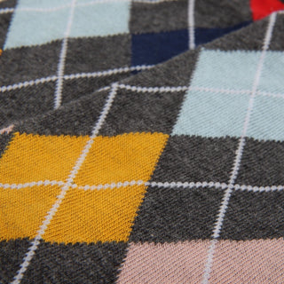 Close-up of a fabric with a argyle pattern featuring yellow, gray, blue, and pink colours.