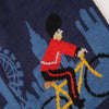 Knitted design of a Royal Welsh Guard on a bicycle with a London landscape background
