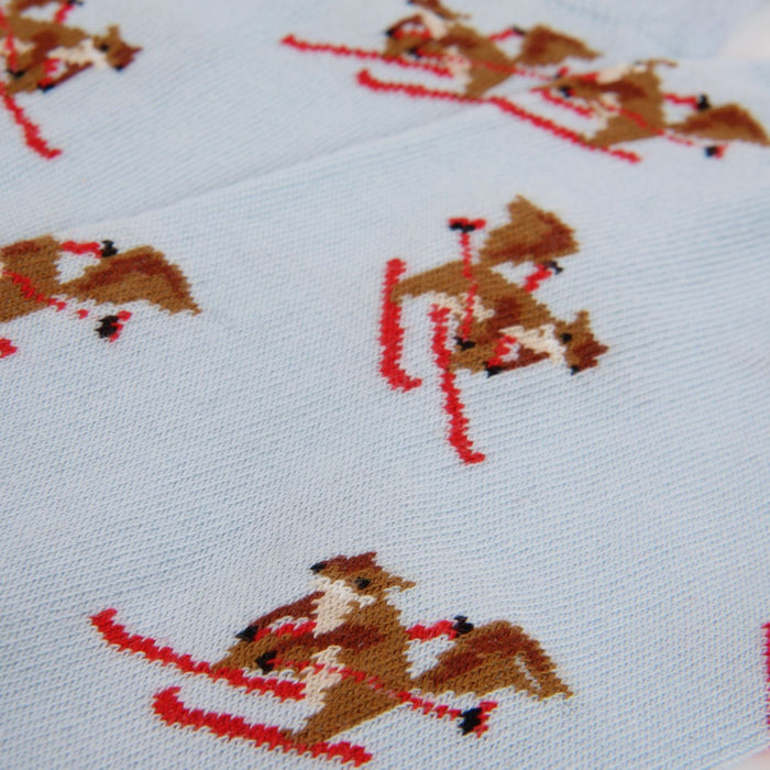 Cross-stitched pattern of a squirrel on skis on a pale blue fabric