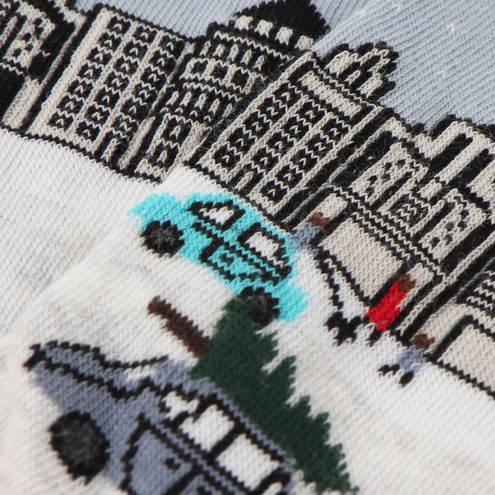 A pair of women's socks with a Christmas in the city scene design, featuring a snow-covered street, buildings, and decorative elements.
