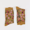 Pair of mustard yellow socks with floral pattern on a white background