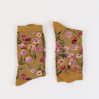Pair of mustard yellow socks with floral pattern on a white background