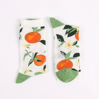 Pair of socks with oranges and a leaf pattern on a white background