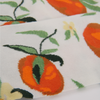 Close-up of fabric showing oranges  and leaves on a white backgroundnd 