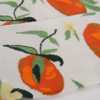 Close-up of fabric showing oranges  and leaves on a white backgroundnd 
