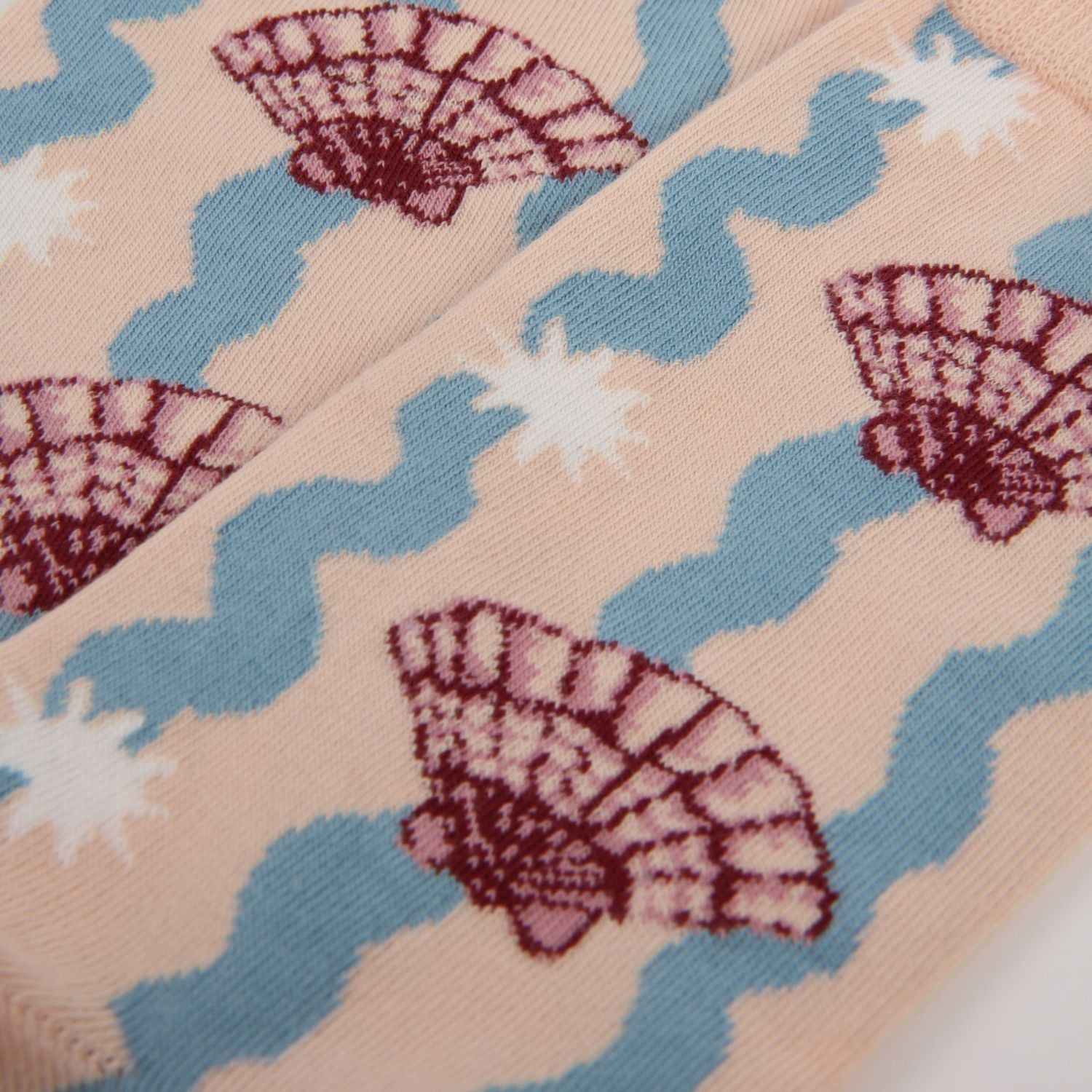 Close-up of fabric with shell and wave pattern on a pink background