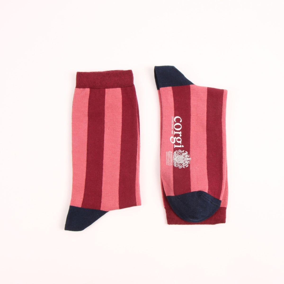 A pair of striped knee-high socks laid flat on a white background. The socks feature vertical stripes in dark red, pink, and light pink, with solid dark red cuffs, navy blue heels, and navy blue toes.