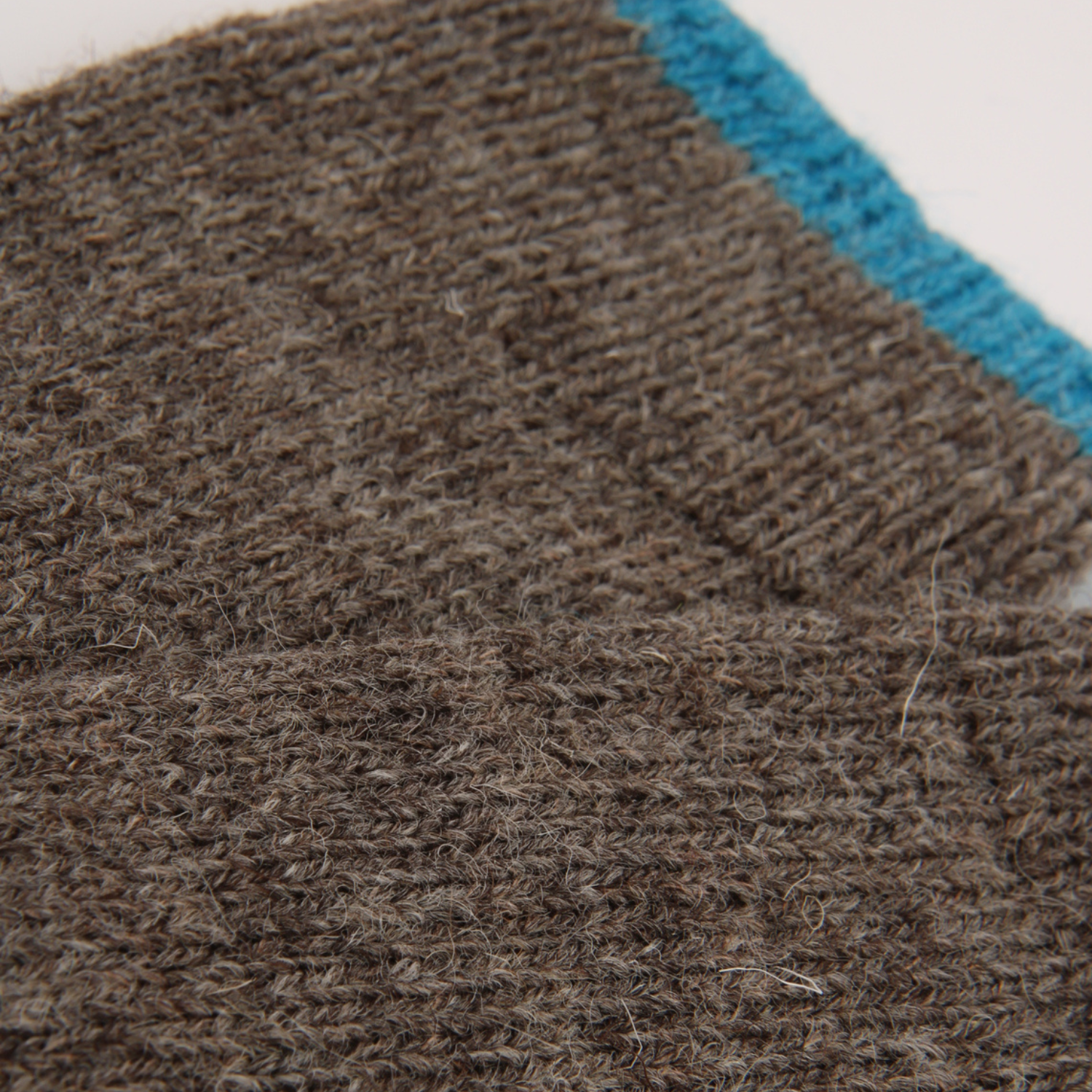 Close-up of a brown textured knit fabric with a bright blue stripe along the edge.