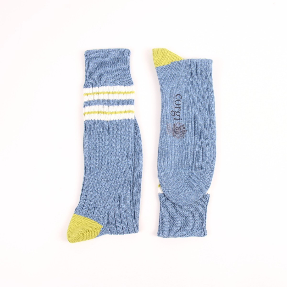 A pair of light blue ribbed crew socks shown flat on a white background, with yellow accents on the toes and heels and white and yellow stripes near the cuff. The brand name 'corgi' is printed vertically on one sock.