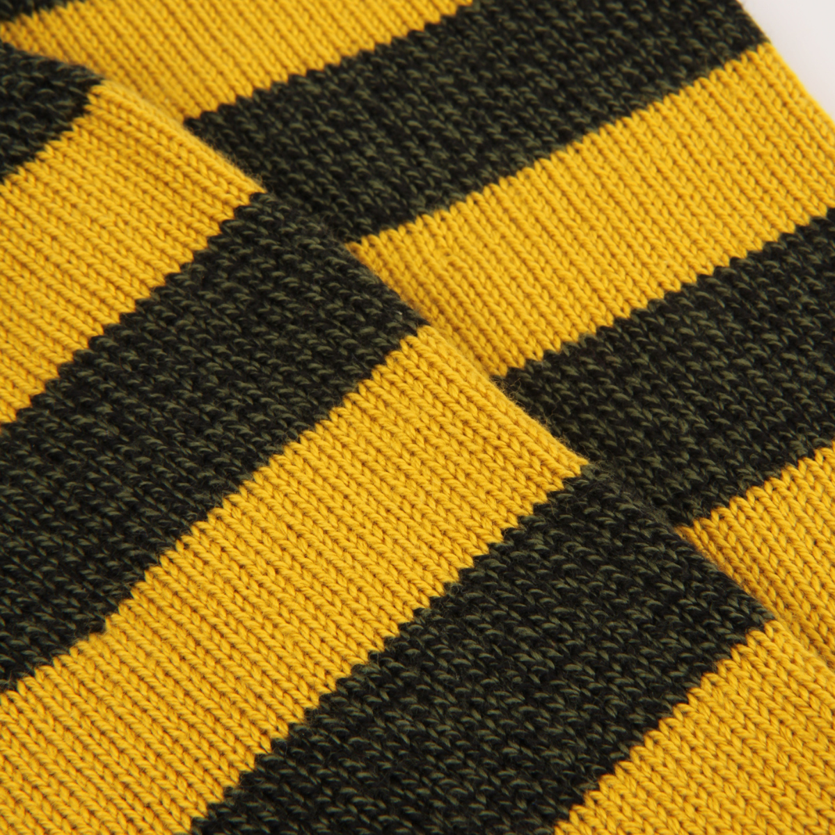 Close-up of a knitted fabric with bold diagonal stripes in mustard yellow and very dark olive green.