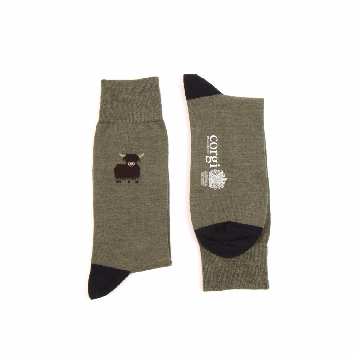 A pair of olive green crew socks with black heels and toes, displayed flat against a white background. One sock features a small black highland cow graphic, and the other displays the brand name 'corgi' in white text alongside a small crest.