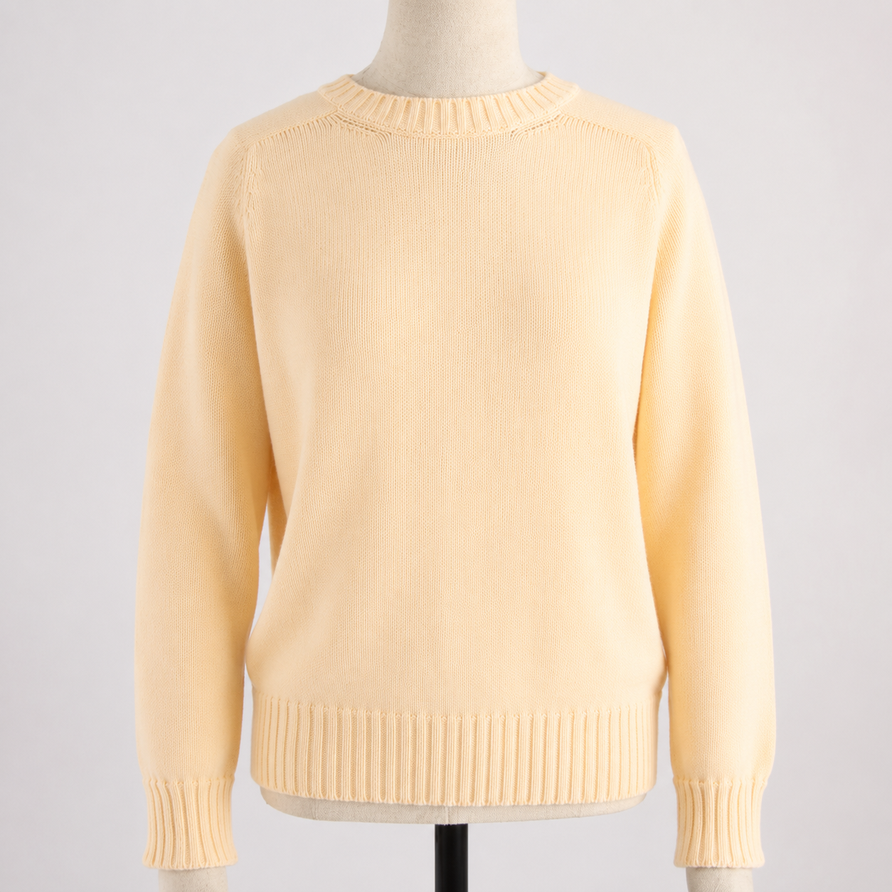 Yellow sweater on a mannequin against a light gray background