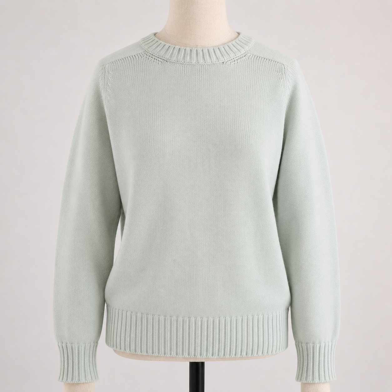 Light green sweater on a mannequin against a light pink background