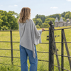 Woman standing by a gate in a field with a castle in the background