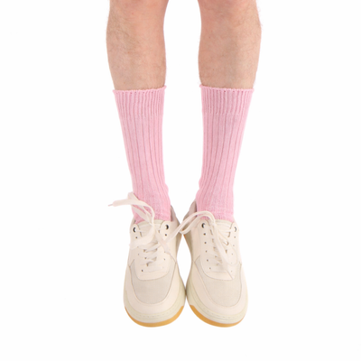 Pink socks worn with white sneakers on a white background