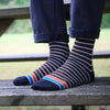 Striped socks worn by a person sitting on a wooden bench outdoors.
