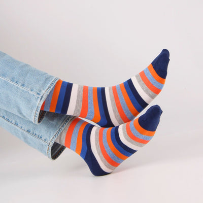 Colorful striped socks worn with light blue jeans on a white background