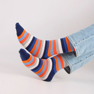 Colorful striped socks worn with light blue jeans on a white background