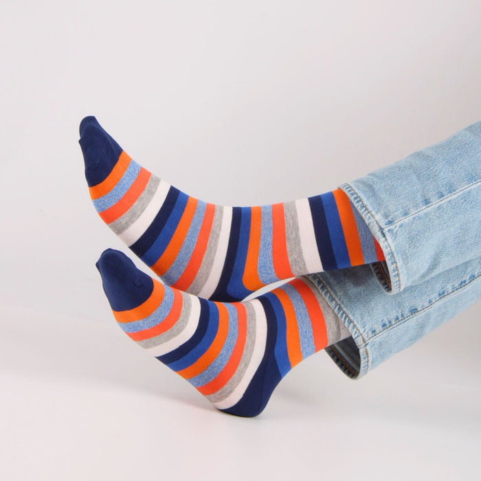 Colorful striped socks worn with light blue jeans on a white background