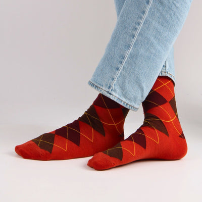 Rust and Port patterned socks worn with light blue jeans on a white background