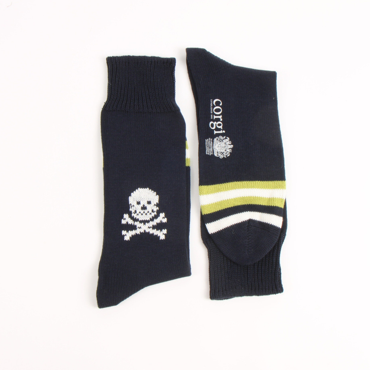 A pair of dark navy crew socks displayed flat against a white background. One sock features a white pixelated skull and crossbones design, while the other shows the toe area with white and lime green stripes and the brand name 'corgi' printed in white.
