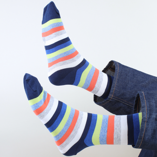 Colourful striped socks worn with jeans on a light background