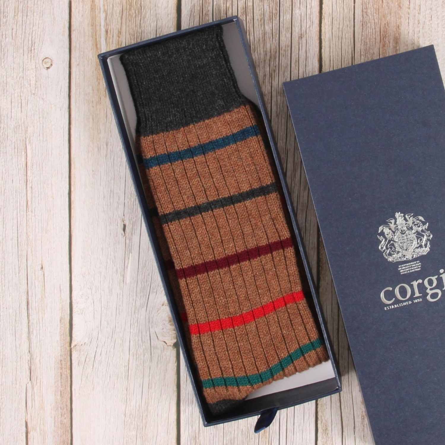 Striped sock in a box with a visible brand logo on a wooden surface