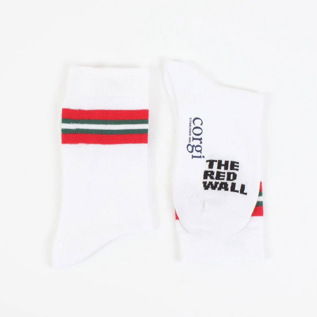 A pair of white crew socks with red and green stripes on the calf, featuring text 'RED WALL' and the flag of Wales.