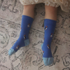 Blue socks with puffin design worn by a child on a patterned carpet