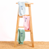 Wooden stool with three colourful pairs of socks hanging on it against a white background