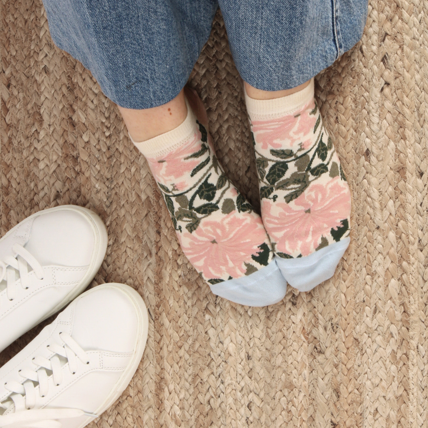 Floral-patterned socks worn with white sneakers on a textured surface