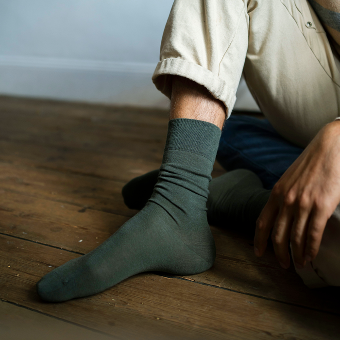 Person wearing green socks sitting on a wooden floor.