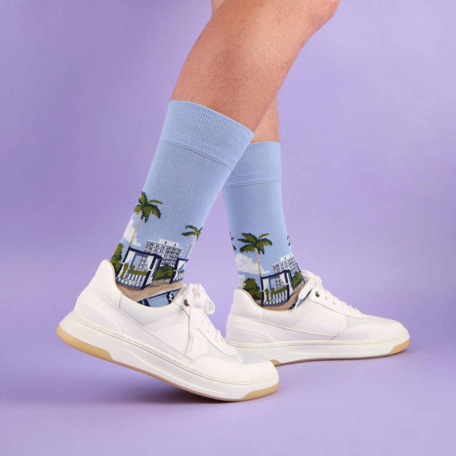 Person wearing light blue socks with a palm tree design on a light blue background
