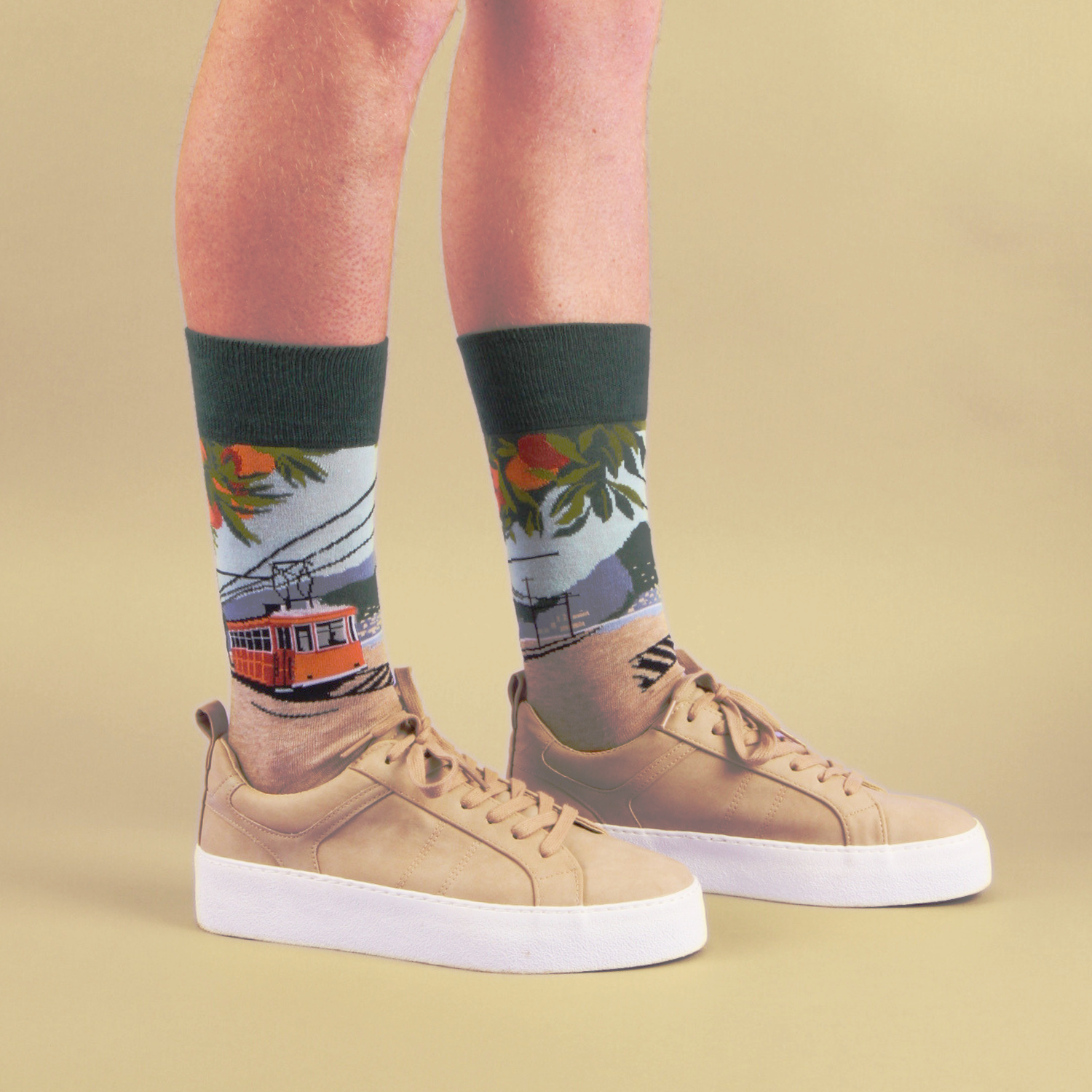 Person wearing socks with a tram design and tan sneakers on a beige background