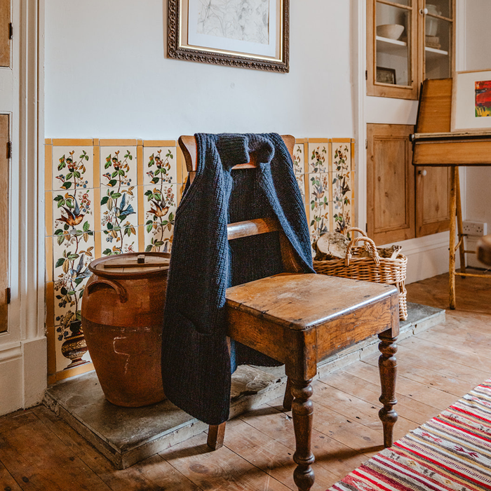 Vintage wooden chair with a blue garment draped over it in a rustic room.