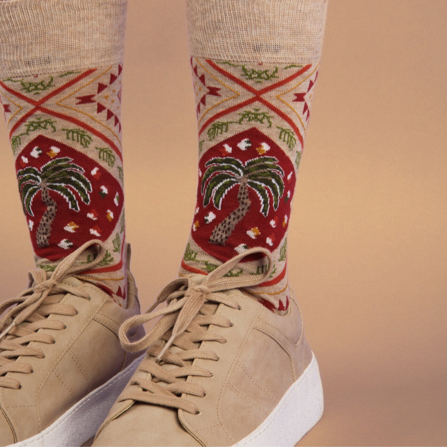 Beige sneakers with patterned socks featuring palm trees on a beige background