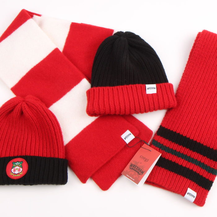 Collection of red and black knit hats and scarves on a white background