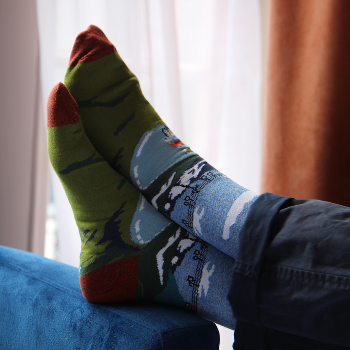 person wearing cycling scene socks with feet up on a blue chair.