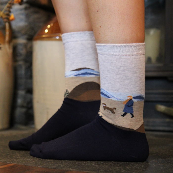 Person wearing socks with scenic beach scene socks in a home setting