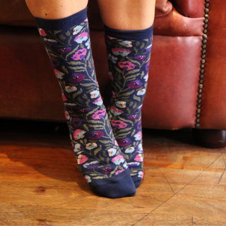 Person wearing floral socks on a wooden floor with a brown leather chair in the background.