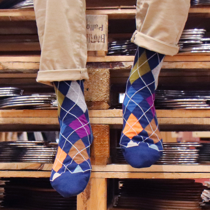 Person wearing colorful argyle socks standing on a wooden pallet.