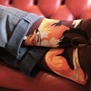 person wearing fox socks on a red sofa.