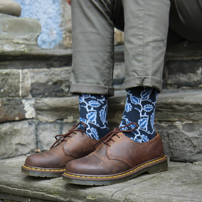 Person wearing brown leather shoes and blue patterned socks on stone steps.