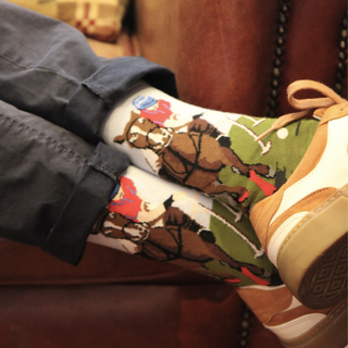 Colorful socks with horse design worn by a person sitting on a couch.