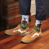 Person wearing tan sneakers and navy pants with socks featuring horse illustrations on a wooden floor.