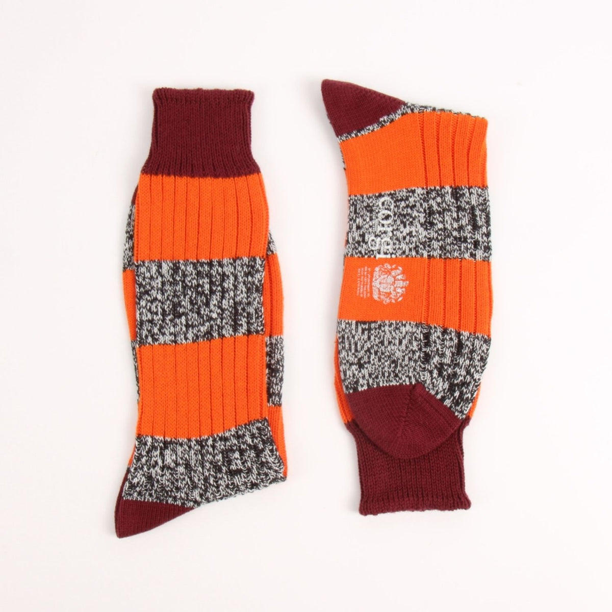 A pair of striped crew socks laid flat on a white background. The socks feature alternating bands of solid bright orange, gray and white heathered knit, and dark burgundy.