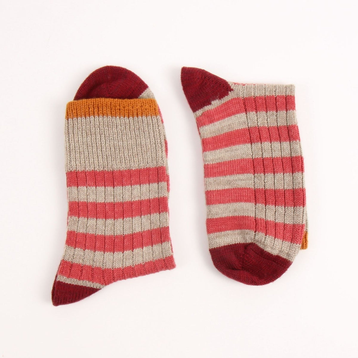 A pair of ribbed crew socks with horizontal stripes in dusty red, light beige, and orange, shown flat on a white background.