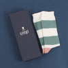 A pair of women's cashmere and cotton colour block socks with stripes in green and pink shades, and a gold toe with gift box.