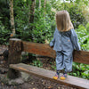 Child standing on a wooden bench in a forest setting